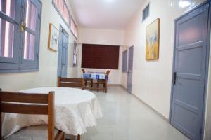 a room with a table and chairs and a blue door at Quintal di Maria in Guediawaye