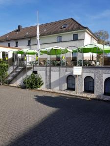 um edifício com mesas e guarda-chuvas verdes em frente em Hotel Bürgergesellschaft em Betzdorf