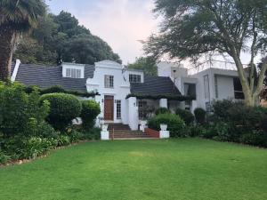 een wit huis met een gazon ervoor bij Fever Tree Suites in Johannesburg