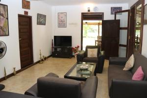 a living room with a couch and chairs and a tv at Thal Sewana Home Stay in Sigiriya