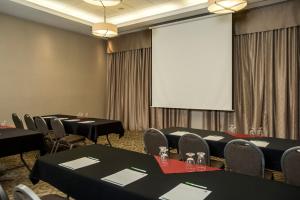 a room filled with tables and chairs with a projector screen at Holiday Inn Lethbridge, an IHG Hotel in Lethbridge