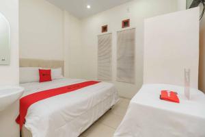 a white bedroom with two beds and a sink at RedDoorz @ Haraito Tarutung in Tarutung