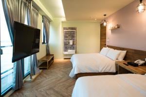 a hotel room with two beds and a flat screen tv at Chance Villa 262 in Jiaoxi