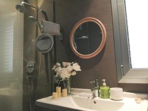 La salle de bains est pourvue d'un lavabo, d'un miroir et de fleurs. dans l'établissement Ático con Fantásticas Vistas al Mar y la iglesia, à Sitges