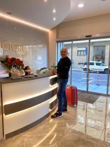 un hombre parado en un mostrador en un hotel en Hotel Victoria en Cuneo