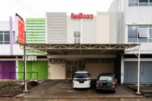 twee auto's geparkeerd op een parkeerplaats voor een gebouw bij RedDoorz @ Graha Cemerlang Maros in Makassar