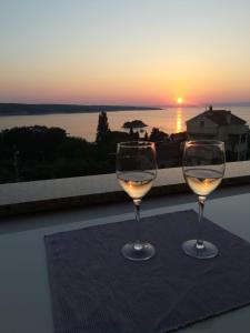 dos copas de vino sentadas en una mesa con la puesta de sol en Apartment Nana, en Supetarska Draga