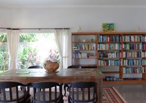 a dining room table with chairs and a book shelf with books at Villa Paradise Lovina in Temukus