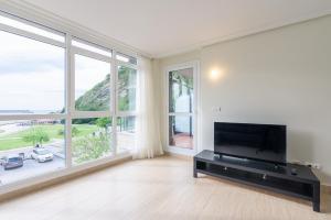a living room with a flat screen tv and large windows at Balea 5 - Local Rentss in Orio