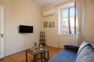 a living room with a blue couch and a tv at San Nicolo dei Vecchi Casa by CorfuEscapes in Corfu Town