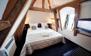 a bedroom with a bed and a flat screen tv at Bilderberg Château Holtmühle in Venlo