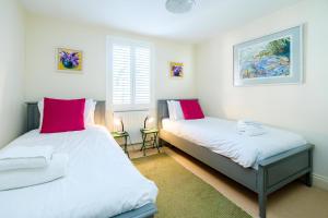 2 Betten in einem Schlafzimmer mit roten und weißen Kissen in der Unterkunft Shell Cottage in Aldeburgh