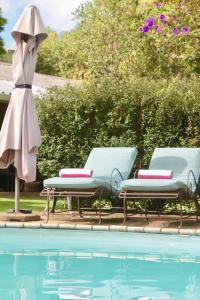 a pool with two lounge chairs and a umbrella next to a pool at Cathkin Cottage Bed & Breakfast in Champagne Valley