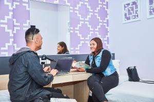 a man and a woman sitting at a desk with a laptop at ibis budget Singapore Joo Chiat in Singapore