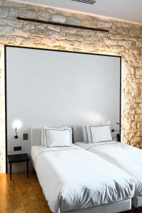 2 bedden in een slaapkamer met een stenen muur bij S Paul City Hotel in Limassol