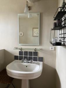 uma casa de banho com um lavatório branco e um espelho. em Le Mas de la Martelière em Le Thor