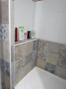 La salle de bains est pourvue d'une baignoire revêtue de carrelage. dans l'établissement Le Chant Des Fees, à Notre-Dame-de-Courson
