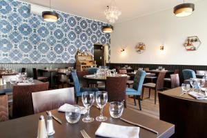 a restaurant with tables and chairs and a wall with blue tiles at Logis Hotel & Restaurant de la Basilique in Albert