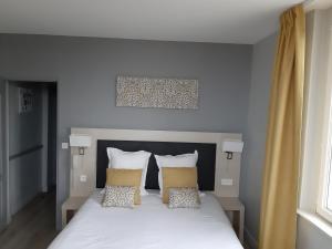a bedroom with a white bed with two pillows at Les Embruns in Trouville-sur-Mer