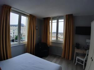 a bedroom with a bed and two large windows at Les Embruns in Trouville-sur-Mer
