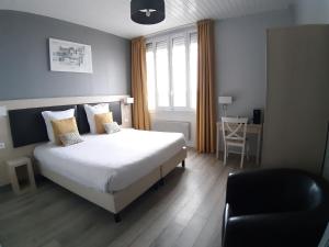 a bedroom with a bed and a chair and a window at Les Embruns in Trouville-sur-Mer