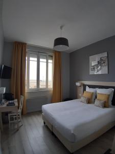 a bedroom with a bed and a desk and a window at Les Embruns in Trouville-sur-Mer