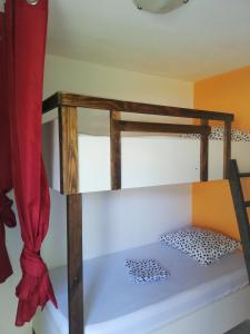 a bunk bed in a room with a red curtain at Appartement idéal famille, vue sur mer. in Le Moule