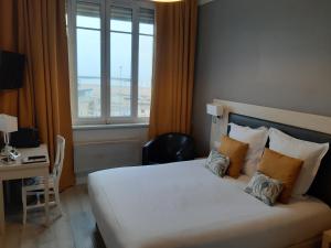 a bedroom with a bed and a desk and a window at Les Embruns in Trouville-sur-Mer