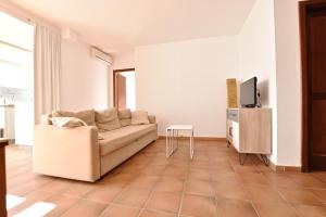 Casa Bom apartamentos في Tahiche: غرفة معيشة مع أريكة وتلفزيون