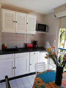 cocina con armarios blancos y mesa en Appartement idéal famille, vue sur mer., en Le Moule