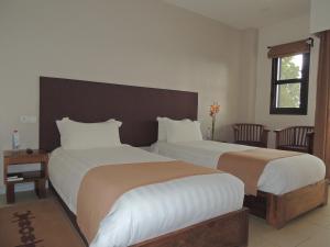 a bedroom with two beds and a window at Plumeria Hotel in Antsirabe