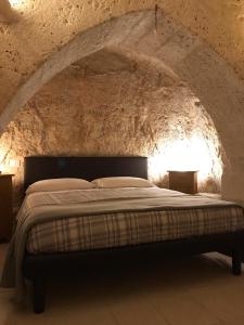 1 dormitorio con 1 cama en una pared de piedra en B&B La Corte, en Matera