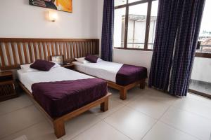 a hotel room with two beds and a window at Port View City Hotel in Colombo