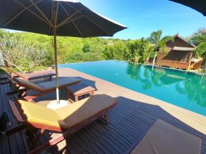 a deck with chairs and an umbrella next to a swimming pool at Molyka Lodge in Banlung