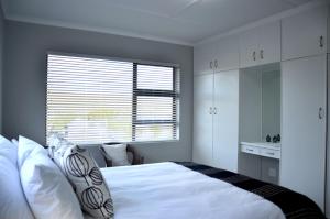 a bedroom with a large white bed and a window at Beach Blessings, Fun in the sun in Stilbaai
