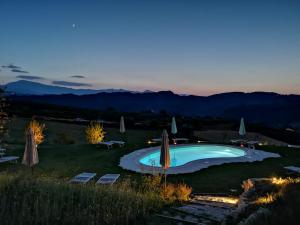 a swimming pool in a field with umbrellas at Residenza Case Pacifici in Ascoli Piceno