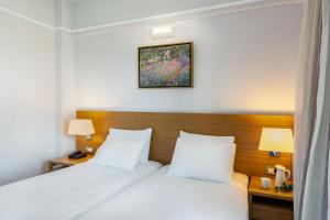 a hotel room with two beds and two lamps at Porto Platanias Village Resort in Plataniás