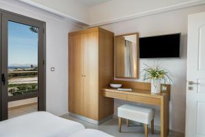 a hotel room with a desk and a tv at Porto Platanias Village Resort in Plataniás