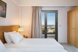 a hotel room with a bed and a window at Porto Platanias Village Resort in Plataniás
