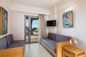a living room with a couch and a table at Porto Platanias Village Resort in Plataniás