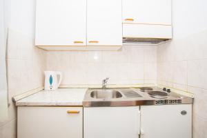 a kitchen with white cabinets and a sink at Apartmani Pava in Omiš +77 photos
