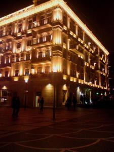 un edificio iluminado con gente parada frente a él en Azcot Hotel, en Baku