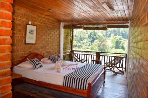 a bedroom with a bed in a room with a balcony at Rafters Retreat in Kitulgala