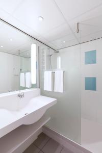 a white bathroom with a sink and a mirror at Novotel Rotterdam - Schiedam in Schiedam