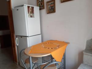 einen Tisch mit einer orangenen Decke neben einem Kühlschrank in der Unterkunft La Dimora del Beato in Martina Franca