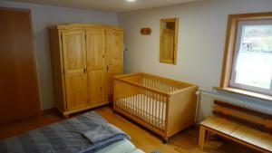 a bedroom with a crib and a wooden cabinet at Ferienhaus Broche in Hilchenbach