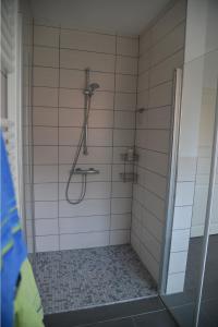 een douche in een badkamer met witte tegels bij Appartements AM ROSENGARTEN in Celle