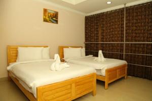 2 Betten in einem Hotelzimmer mit weißer Bettwäsche in der Unterkunft TRISTAR REGENCY HOTEL in Ernakulam