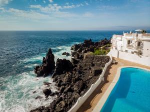 a villa with a swimming pool next to the ocean at Ocean shore apartment 2 in Puerto de Santiago