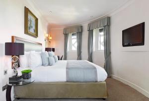 1 dormitorio con 1 cama grande y TV en The Royal Horseguards Hotel, London, en Londres